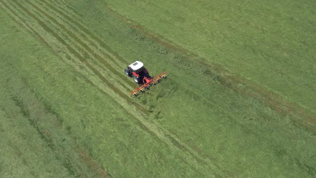 Aerial - Tractor turning grass to make hay in spring