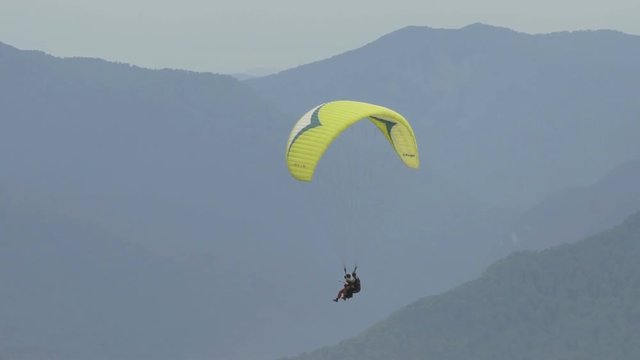 Parachute sliding with two people over mountains in slow motion