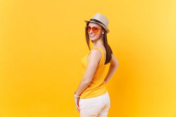 Back rear portrait view of young woman in straw summer hat, orange glasses looking turned back,...