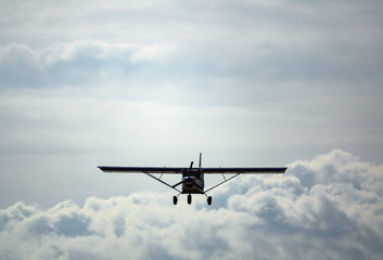 Light aircraft flying over cloudy sky, front view