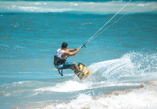 Kitesurfing. The young man is flying on the sea wave on the Board.