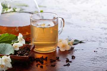 Green tea with jasmine in cup and teapot on old copper table.