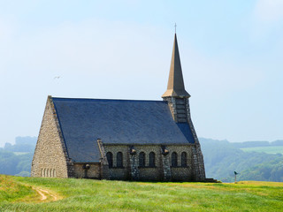 Fototapeta na wymiar Typical Norman church: Chapelle Notre Dame de la Garde on top of the cliff in Etretat, Normandie, France. Picturesque landscape on a sunny day