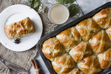Hot cross buns with the cup of coffee, cinnamon sticks on the table flat lay