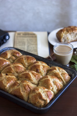 Hot cross buns with the cup of coffee, cinnamon sticks on the table