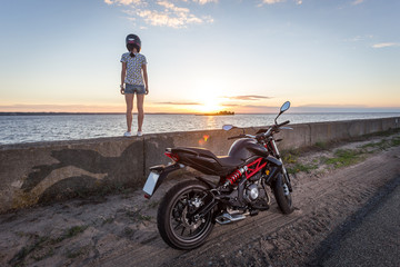 Fototapeta na wymiar woman on road motorbike looking to sunset