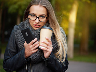 Portrait of a beautiful stylish young blonde with make-up in black leather jacket glasses and a...