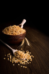 Сhopped peas in a wooden bowl on a wooden background near the ears of wheat. wooden spoon with chopped peas
