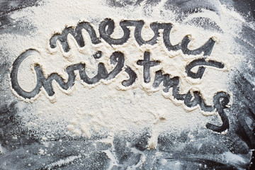 Word of Christmas with white flour on a dark background