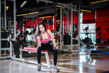 Fototapeta na wymiar Fitness Asian women performing doing exercises training with dumbbell sport in sport gym interior and fitness health club with sports exercise equipment Gym background.