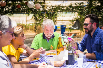 caucasian family having lunch together during a sunny day having fun and smiling while eat italian pasta food. restaurant natural place with cheap dishes and stuffs on the table