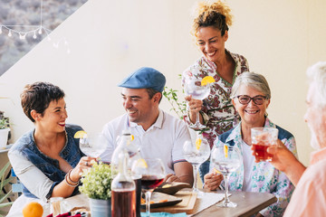 group of caucasian people friends with different ages celebrate together cheering with cocktails all together having fun - party with family and friendship concept - cheerful men and women toasting