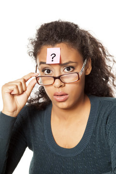 portrait of confused young dark-skinned woman with question mark on her forehead on a white background