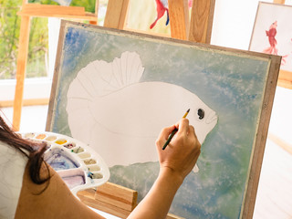 Asian women artrist painting the fish in classroom while her teacher teaching and tutor how to paint,Art fish concept