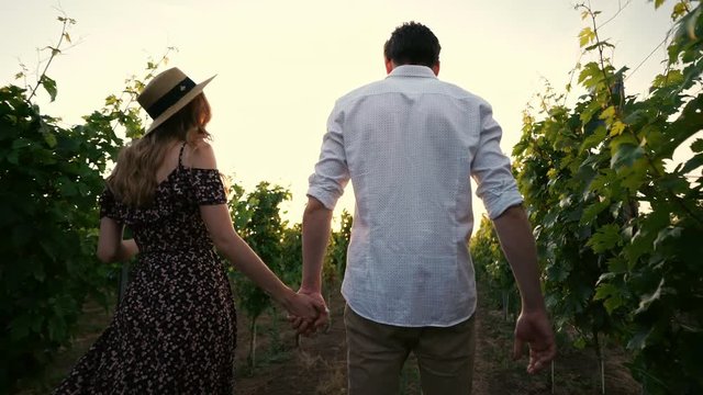 Young happy loving couple walking outdoors in the vineyard talking with each other