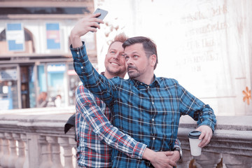 happy gay lifestyle people take a selfie while sight seeing in the city having coffee to go