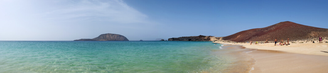Fototapeta na wymiar Isole Canarie: la spiaggia Playa de Las Conchas e la montagna rossa Montana Bermeja a nord di La Graciosa, l'isola principale dell'arcipelago Chinijo a nord ovest di Lanzarote