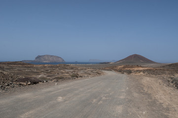 Isole Canarie: la strada sterrata per la spiaggia Playa de Las Conchas e il vulcano Montana Bermeja a La Graciosa, l'isola principale dell'arcipelago Chinijo a nord ovest di Lanzarote