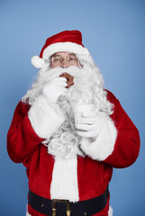 Hungry santa claus eating cookie at studio shot .