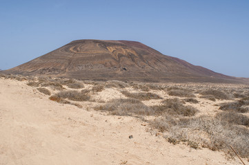 Lanzarote, Isole Canarie: strada sterrata, cespugli e paesaggio desertico con la Montagna Pedro Barba, il vulcano dell'isola La Graciosa