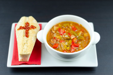 A delicious stew in a white ceramic bowl served with bread in the shape of a coffin