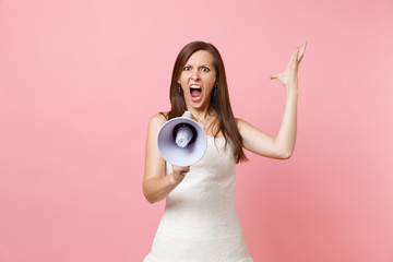 Portrait of angry irritated bride woman in wedding dress screaming in megaphone and spreading hands...