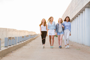 four female friends walking down at walkway, sunshine background
