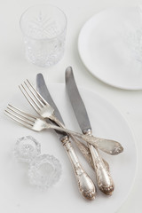 silver silverware. Devices for eating. View from above. Salt for salt from crystal. Knife and fork. White plate.