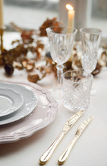 Pink and white plates with golden cutlery! Festive table setting for Christmas or another holiday. Candles and cones decor