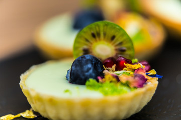 Homemade shortbread tartlets with custard cream and fruit..Tartlets dessert, pastry cakes with fresh fruit on wooden background