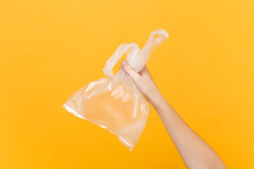 Close up female hold in hand clear empty blank transparent plastic bag full with air for takeaway isolated on bright yellow background. Packaging delivery service concept. Copy space. Advertising area