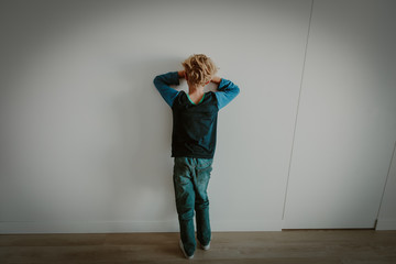 young boy standing up against a wall