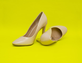 Beige high heel shoes isolated on the yellow background