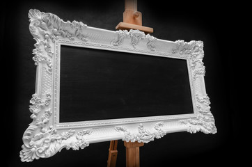 White rococo frame on easel. Black background.