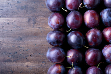 Ripe juicy plums on a wooden background.