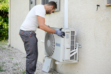 handsome young man electrician installing an air conditioning in a client house