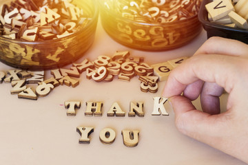 hand woman forming thank you text with small wooden letters