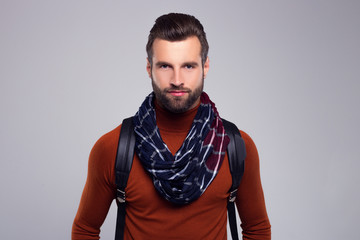  Stylish and casual. Handsome young man in scarf looking at camera while standing against white background