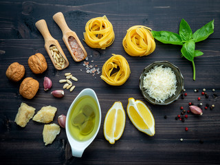 The ingredients for green pesto sauce on dark wooden background.