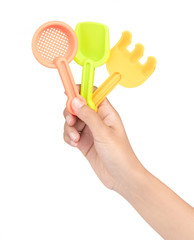 hand holding collection of toy gardening tools isolated on white background.