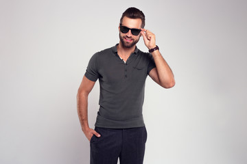 Stubble macho man. Handsome young man in sunglasses looking at camera while standing against white background