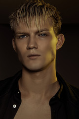 Handsome stripped blonde male model wearing black suit on black isolated font background