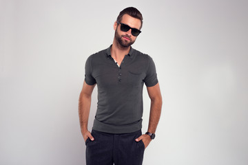 Modern and charming. Handsome young man in sunglasses looking at camera while standing against white background