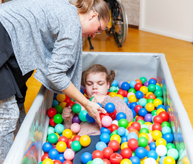 Fototapeta na wymiar Disability a disabled child having play therapy together with an experienced special needs carer.