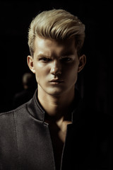 Handsome stripped blonde male model wearing black suit on black isolated font background