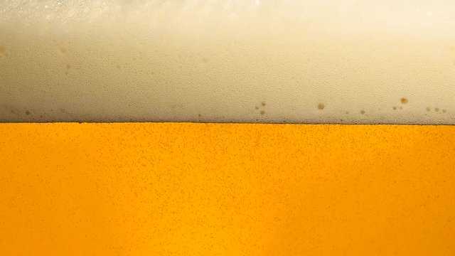 Close up pouring beer with bubbles in glass