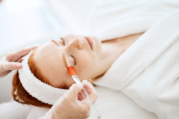 Face Skin Care. Unrecognizable beautician applying moisturising vitaminic gel on face using brush...