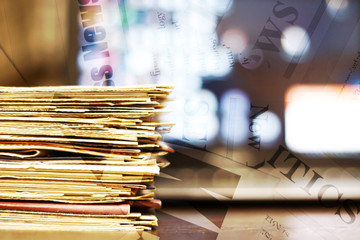 Newspaper background. Pile of papers with news and blurred sceen of laptop, partially shown words, headlines and articles as overlay texture 