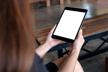 Mockup image of a woman holding black tablet pc with white blank desktop screen in cafe
