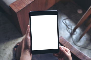 Top view mockup image of a woman sitting and holding black tablet pc with blank white desktop screen